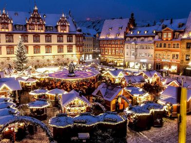 Ansicht des beleuchteten Weihnachtsmarktes Coburg mit historischen Gebäuden im Hintergrund.